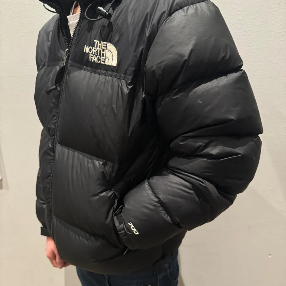 Säljer en svart pufferjacka från The North Face. Modellen är -176- cm och väger 68kg. Jackan har en dragkedja och är perfekt för kalla vinterdagar. Den är i bra skick men har ett litet hål på baksidan som man ej ser. Stor logga på bröstet och ryggen. Perfekt för dig som vill hålla dig varm och stilren! Pris kan diskuteras vid snabb affär . Jackor.