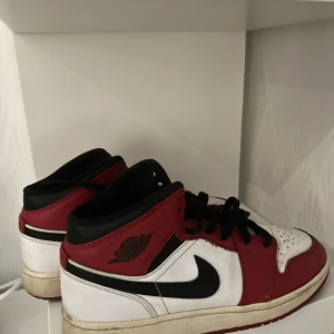 Nike Air Jordans i rött, svart och vitt - Säljer ett par klassiska Nike Air Jordans i rött, svart och vitt. Skorna har snörning och är i bra skick! Köpta från footlocker, skriv vid intresse!