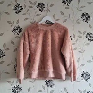 Rosa fluffig tröja från Amisu, Strl: M/38/40 - Mysig rosa fluffig tröja från Amisu i storlek M. Perfekt för kyliga dagar med sin fluffiga och varma design. Tröjan har långa ärmar och ribbade muddar vid ärmslut och nederkant. Superbekväm och stilren för både vardag och mysiga hemmakvällar. 🧡