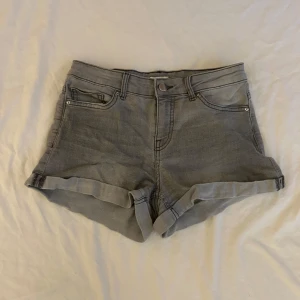 Grå jeansshorts - Säljer ett par grå jeansshorts i storlek 34, med uppvikta benslut. Perfekta för sommardagar eller en avslappnad vårlook. De är i bra skick och redo för en ny ägare!