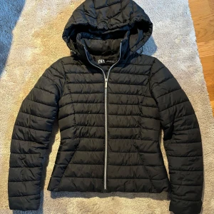 Svart pufferjacka från Zara - Säljer en svart pufferjacka från Zara i storlek XS i mycket bra skick. Jackan har en dragkedja framtill och en mysig huva. Perfekt för kyliga höst dagar. Den är lätt och bekväm att bära, med en stilren design som passar till det mesta. 🖤