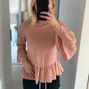 Rosa topp från Pieces - Säljer en superfin rosa topp från Pieces i storlek XS. Den har trekvartsärmar med volangdetaljer och en söt volangkant nedtill. Perfekt för både vardag och fest! 