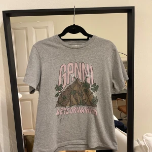 Grå t-shirt från Ganni - 📣INTRESSE KOLL📣grå t-shirt från Ganni med tryck framtill som säger 'Let's Grow Wild'. Den är kortärmad och i ett tjockare bomullsmaterial.