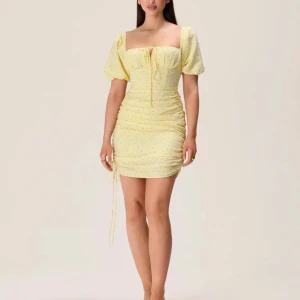 Gul kortklänning från ADOORE - Säljer en superfin gul klänning från ADOORE i nytt skick. Klänningen har en söt prickig design och korta puffärmar. Den är tight och har en snygg snörning framtill. Perfekt för sommarens fester eller en solig dag ute. Storlek dam 34.