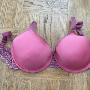 Rosa bh från Twilfit - Säljer en rosa bh från Twilfit i storlek 70F. Den har lätt vadderade kupor och spetsdetaljer på sidorna. Axelbanden är justerbara. Perfekt för både vardag och speciella tillfällen! 💖