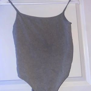 Grå ribbad linnebody - Säljer en stilren grå ribbad linnebody med smala axelband. Perfekt för lager-på-lager eller att bära som den är under varma dagar. Den har en enkel och tidlös design som passar till det mesta. Perfekt för både vardag och fest!