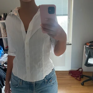 Vit randig skjorta - Säljer en vit skjorta med vita diskreta ränder. Skjortan har en normal passform och är tillverkad i ett lätt och bekvämt material. Passar perfekt med jeans eller kjol! Kontakta mig vid frågor💕