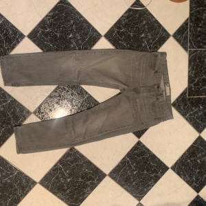 Grå jeansbyxor - Säljer ett par grå jeansbyxor i bra skick. De har en klassisk femficksdesign och är perfekta för vardagsbruk. Passar till både avslappnade och mer uppklädda tillfällen. Perfekt för höst och vår!