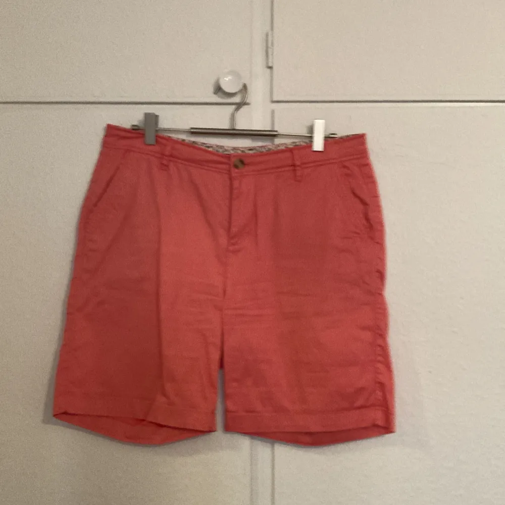 Säljer ett par snygga rosa shorts i mycket bra skick. De har en klassisk design med knappar och fickor både fram och bak. Perfekta för sommardagar eller en avslappnad vårutflykt. Passar bra till både t-shirt och skjorta!. Shorts.