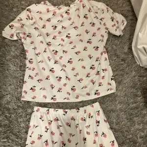 Säljer ett vitt pyjamas set med blommönster. De är gjorda i mjuk bomull och har en elastisk midja för extra komfort. Observera att det finns en liten foundation fläck på shortsen, men det går nog lätt ut i tvätten. Passar bra till avslappnade tillfällen eller som mysplagg hemma. Jätte mysigt tyg och perfekt att sova i . Tror den är i stl M, och kommer inte ihåg vart jag köpte den ifrån. Använd några gånger.