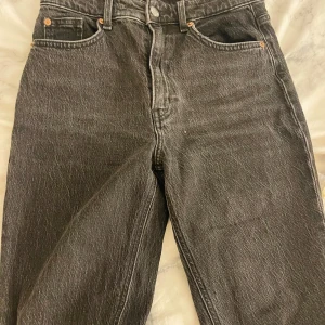 Svarta jeans med fransiga kanter - Säljer ett par svarta jeans i mycket bra skick. De har en klassisk femficksdesign och hög midja. Jeansen har en straight passform och fransiga kanter vid bensluten för en trendig look. Perfekta för både vardag och fest!