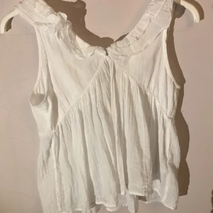 Vitt linne från gina 🩷 - Säljer en söt vit ärmlös topp från Gina Tricot, har använts typ en gång.Den har volangdetaljer vid axlarna och en knytning baktill. Perfekt för sommardagar. Toppen är i ett lätt och luftigt material.Säljer då den inte passar mig🌺