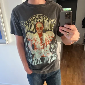 Elton John t shirt - Säljer denna tshirten från reclaimed vintage som har riktigt häftig färg och sömn som syns vid öppningarna. Den har använts väldigt få gånger, nästan som  ny. Storlek S men sitter oversized