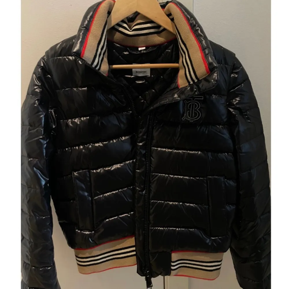 Säljer en Burberry jacka för dam i nyskick då den aldrig kom till användning. Köpt för 8500kr.  Går att göra till väst.  Modell: Burberry Hessle Detachable Sleeve Icon Stripe Down Puffer Jacket Storlek: M Style Number: 8070219. Jackor.