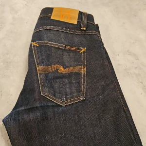 Nudie grim tim - Strl 29-30 i materialet dry selvedge. Skicket är använt men bra. Se bilder.