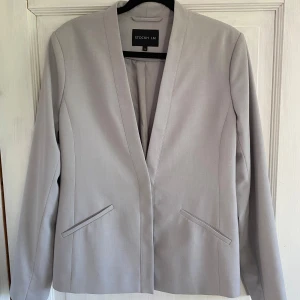 Snygg stilren kavaj från STOCKH LM - Supersnygg kavaj säljes. Ljusgrå med enkel knäppning (en knapp). Mycket gott skick då den knappt är använd, alltså som ny! 