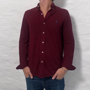 Vinröd skjorta med knappar - Säljer en snygg vinröd skjorta från Ralph Lauren i bra skick. Featherweight mesh! 