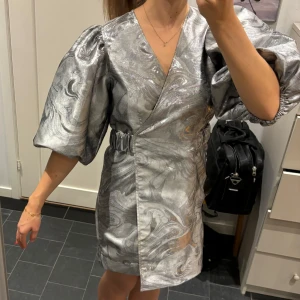 Ganni klänning  - Coolaste klänningen i silver med puffärmar ifrån Ganni🥰 använd 1 gång så i väldigt fint skick!
