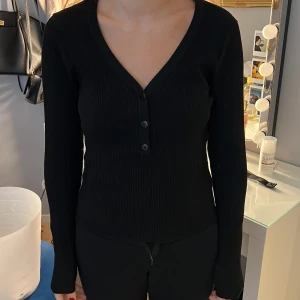 Svart ribbad tröja  - Säljer en jättefin tröja från Gina, storlek L, men passar min syster som har XS/S, jätte fin knapparna går även att ha öppna
