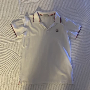 Moncler Piké  - En vit moncler pike i storlek M har haft den i ca 2 månader. Köpt för 1200 men kan släppa den vid 600-700 eller mot ett byte. DEN ÄR EJ ÄKTA