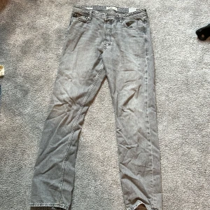 Grå jeans från Jack & Jones - Säljer ett par grå jeans från Jack & Jones i modellen Loose/Chris. De är i en loose fit och har en klassisk femficksdesign. De är i bra skick och redo för en ny ägare!