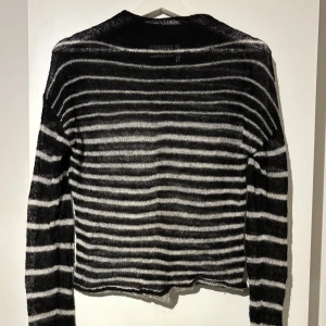 Stickad tröja - Tunt stickad randig tröja från weekday med medelhög krage. Då tröjan är tunt stickad är den lite see through. Armarna är väldigt långa men det är ett hål i vänster arm. 