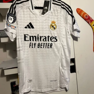 Real Madrid tröja 2024/25 - Helt ny real Madrid tröja med mbappe tryck bakom. Nya ställ. Det är spelar version, då sitter det mer tajtare. Storlek på tröjan är M (Slim fit). Tröjan har också Champions league tryck vid armarna.