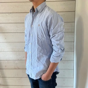 Raffe skjorta - Säljer en stilren ljusblå Ralph lauren skjorta. Skjortan har långa ärmar och knappar hela vägen ner. Perfekt för både vardag och fest! 10/10 skick. Har typ aldrig använt. Tveka inte att höra av dig