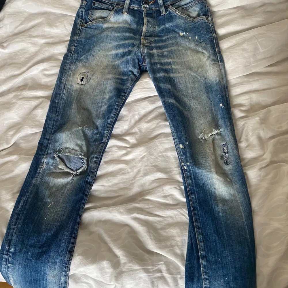 Säljer ett par snygga blå jeans från Jack & Jones. De har en cool slitning och lite färgstänk för en avslappnad look. Modellen är slim fit och heter Glenn. Perfekta för en casual stil! 29 W 30 L. Jeans & Byxor.