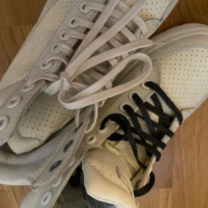 Vita sneakers med hög snörning - Säljer ett par Dr martens med hög snörning.  Skorna har både vita och svarta skosnören, helt oandvända💞köptes för 1200 men säljer för 1000 men pris kan alltid diskuteras💞