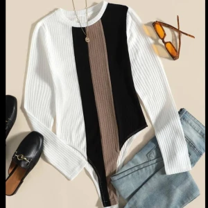 Randig ribbad bodysuit från Shein - Säljer en supercool randig bodysuit i storlek 38. Den är ribbad och har långa ärmar, perfekt för höst och vår. Färgerna är en snygg mix av vit, svart och beige. Passar perfekt till både jeans och kjol för en stilren look!