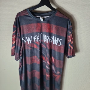 Svart och röd t-shirt, storlek XL/XXL - En svart och röd t-shirt med tryck av Freddy Krueger från Nightmare on Elm Street. På framsidan syns Freddy's hand med klor och texten "Sweet Dreams". På baksidan syns Freddy's hand med klor och texten "One, Two Freddy's Coming for You Three, Four Be