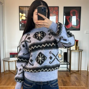 Ljuslila stickad tröja med mönster Zara  - Säljer en supermysig ljuslila stickad tröja med ett coolt geometriskt mönster i svart och vitt. Tröjan har långa ärmar och en normal passform, perfekt för höst och vinter. Den är både varm och stilren, perfekt för att hålla sig snygg och bekväm under kyliga dagar. 🖤❄️