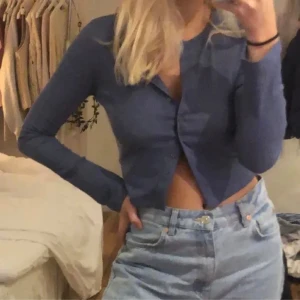 Blå ribbad kofta från Weekday - Säljer en snygg blå ribbad kofta från Weekday. Den har långa ärmar och knappar framtill. Använd fåtal gånger!