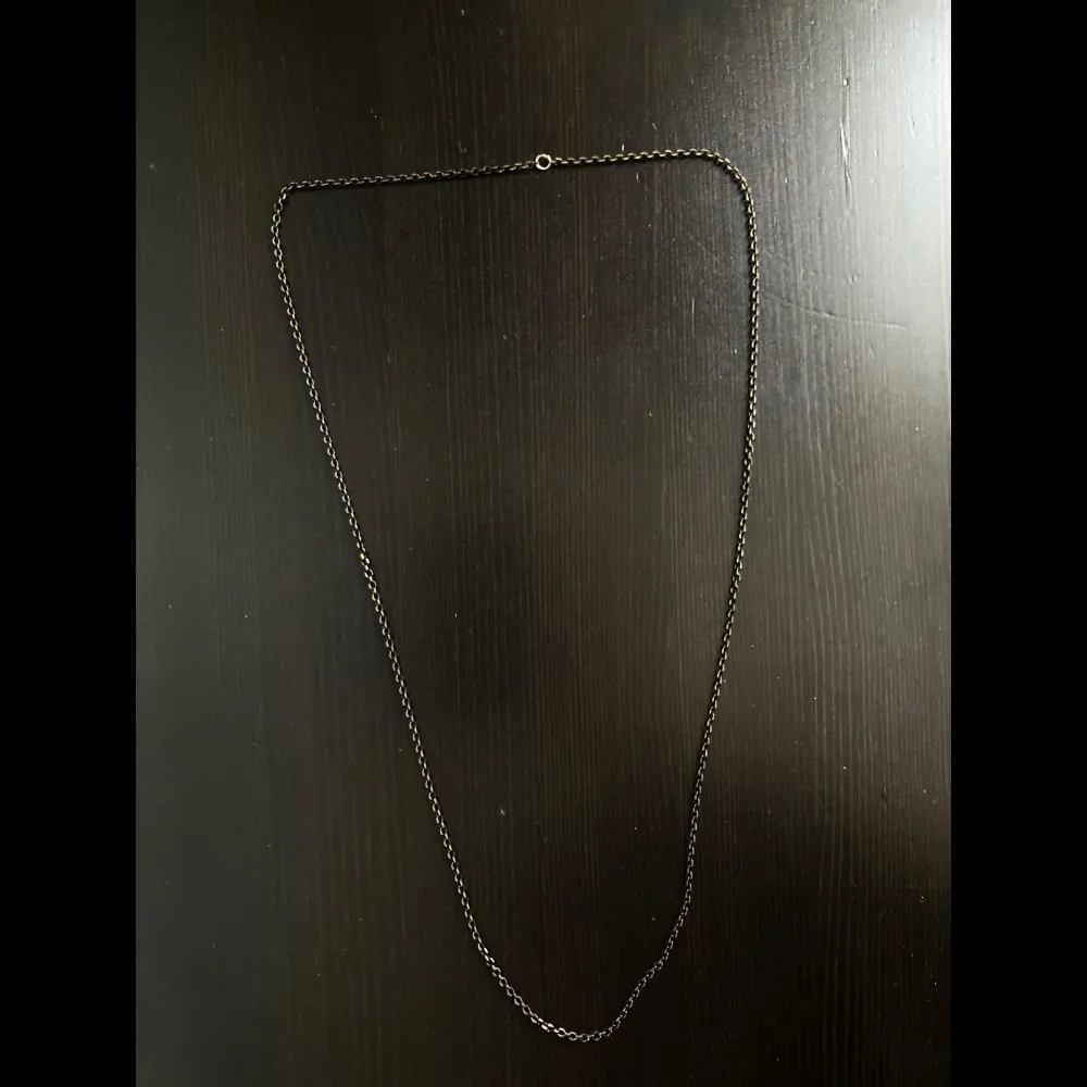 Långt halsband i svart och guldfärgad metall. Längd: 80 cm, bredd: 2 mm.. Accessoarer.