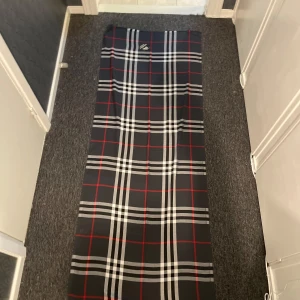 En burberry sjal/halsduk - En stilren och fräsch burberry halsduk med svarta och röda nyanser. Den må vara stor utvecklad med när man viker in den är det nog troligen den finaste halsduken du har haft på dig. (Pris kan diskuteras) 