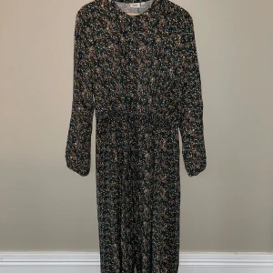 Mönstrad långklänning med snörning i midjan - Mönstrad långklänning från Saint Tropez med knappar hela vägen och snörning i midjan. 