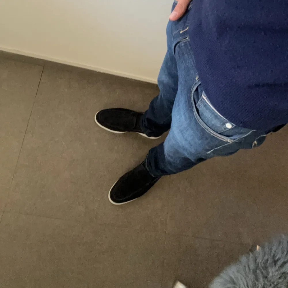 Säljer ett par snygga mörkblå loafers i mocka. De har en stilren design med vit sula som ger en fräsch kontrast. Dessa är storlek 43 men passar på lite större med. Navy blue. Perfekta för både vardag och fest! Skorna är i nyskick och passar perfekt till vilka jeans som helst. Storleken är normal och de är superbekväma att ha på sig. . Skor.