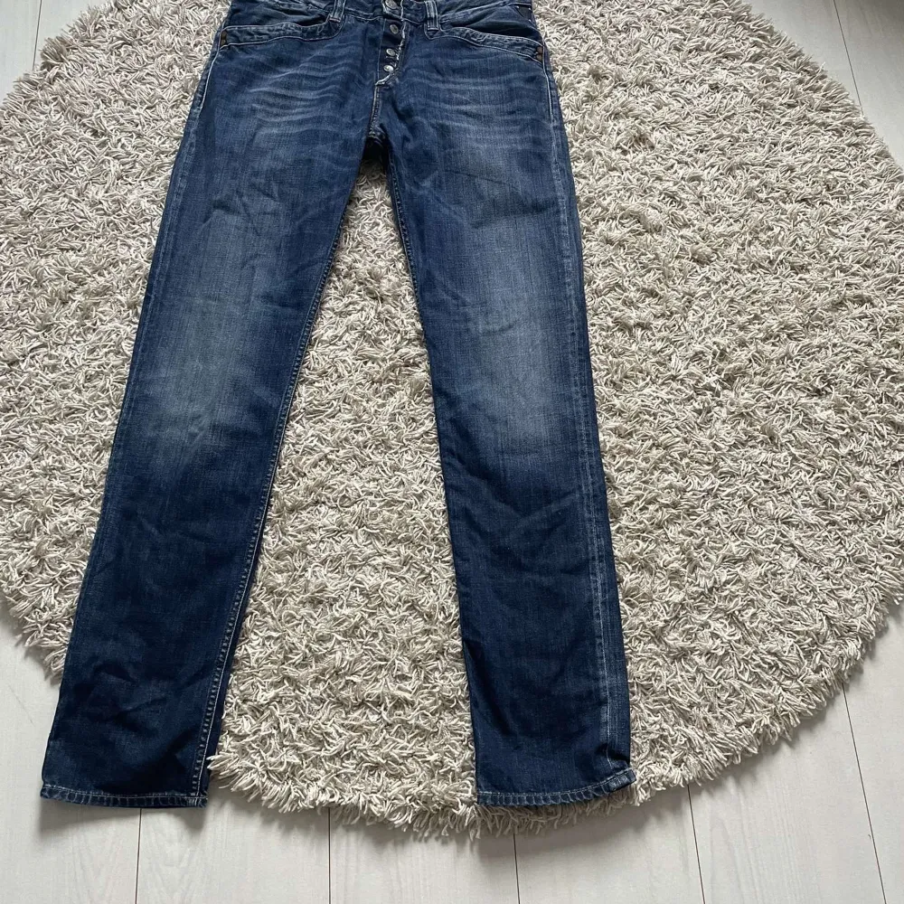 Säljer ett par snygga mörkblå jeans med knappar framtill. De har en klassisk straight fit och är perfekta för både vardag och fest. Jeansen är i bra skick och har en stilren design med fem fickor.30/32. Jeans & Byxor.