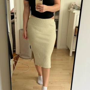 Stickad kjol - Stickad kjol med slits. Beige/cremevit. Har inte använts mycket men är lite nopprig. Tjock o varmt material perfekt t hösten. Den är för liten för mig tyvärr. Strl S
