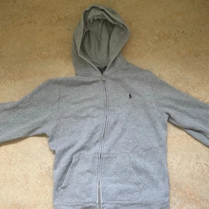 Ralph Lauren Hoodie - Klassisk Ralph Lauren hoodie av bomull i storlek XL 18-20 för pojkar vilket motsvarar ungefär en XS för män., se https://www.ralphlauren.co.uk/en/boys-size-guide/boys_all_ages_apparel.html . Säljes för den blivit för liten. Prisförslag accepteras.