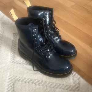 Svarta Dr. Martens kängor - Säljer ett par klassiska svarta Dr. Martens kängor i skinn. De har den ikoniska gula sömmen och en robust sula. Perfekta för höst och vinter, och de är i bra skick med minimal slitage på sulan. Passar både till vardags och fest!