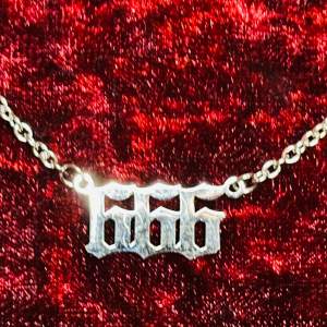 Säljer ett coolt silverfärgat halsband med en 666-berlock. Kedjan är tunn och elegant, perfekt för att ge en edgy touch till din outfit. Talismanen är 1,8 cm lång. Halsbandet är 45 cm, justerbar längd. Gjort i tåligt rostfritt stål. oanvänt. 