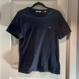 Gant T-shirt svart med loggan på vänster bröst. Mycket fint skick, inga konstigheter. Storlek S men sitter tajt så skulle säga S med slimfit passform. Jag på bild är 173 cm, 60 kg drygt. Hör av dig vid frågor. Mvh 