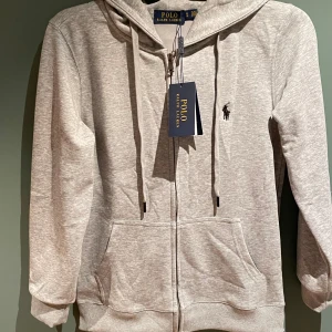 Ralph Lauren zip grå (Kina) - Säljer denna Ralph Lauren tröja, köpte den på en sketchy hemsida (därför lågt pris), fick hem den nyss men den passa ej. Den står storlek M men den är för S.