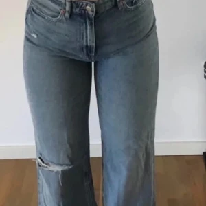 Blå jeans med slitningar - Säljer ett par snygga blå jeans med slitningar på knäet. Storlek 38/40. De är högmidjade och har en straight passform. Perfekta för en avslappnad stil och kan matchas med nästan vad som helst. De är i bra skick och redo för en ny ägare!