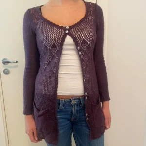 Lila stickad kofta  - Säljer en superfin lila stickad kofta. Den har ett snyggt hålmönster och knappar framtill. Perfekt för höst och vår, och den är långärmad vilket gör den extra mysig. Passar perfekt till jeans eller klänning!