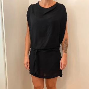 Svart klänning från Redoute Creation - Snygg svart klänning från Redoute Creation i storlek 42. Den är ärmlös och har en lös passform med ett knytband i midjan för en smickrande silhuett. Perfekt för både vardag och festliga tillfällen. Tillverkad i ett lätt och bekvämt material.