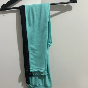 Turkos hoodie med NYC-tryck - Säljer en cool turkos hoodie med stort svart NYC-tryck på framsidan. Den är kortärmad och har en skön luva. Perfekt för en avslappnad stil eller träning. Den har svarta detaljer på ärmarna som ger en extra touch. Passar perfekt till vår och sommar! Med byxorna 