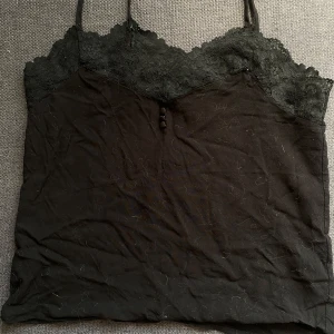 Svart linne från Vero Moda - KATTEN HÅREN KOMMER TAS BORT INNAN JAG SÄNDER VARAN‼️Säljer ett svart linne från Vero Moda med spetsdetaljer vid halsringningen. Perfekt för både vardag och fest. Linnet har smala axelband och en bekväm passform. Passar bra under en kavaj eller som det är.🖤✨